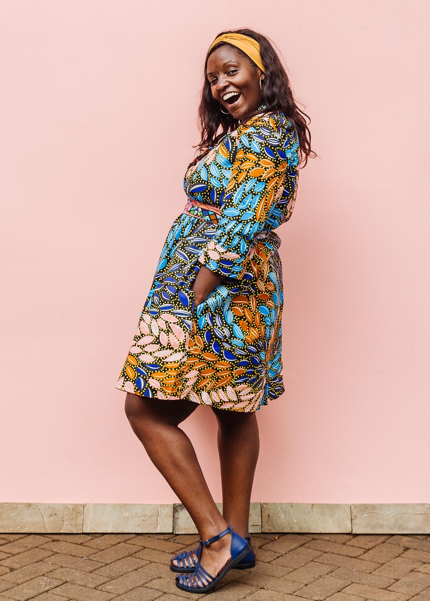 The model is wearing black dress with yellow dots and brown, blues, peach leaves.