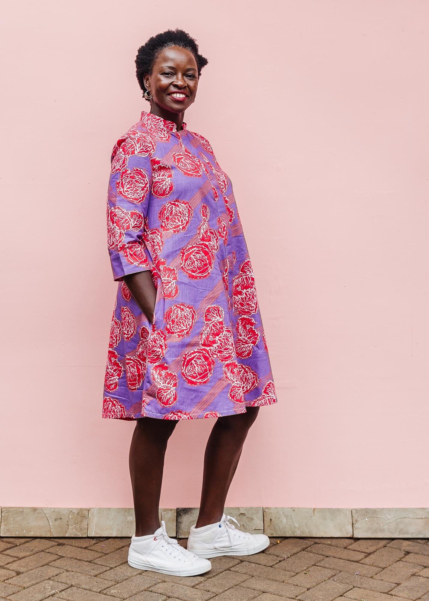 The model is wearing violet dress with red and white cabbages