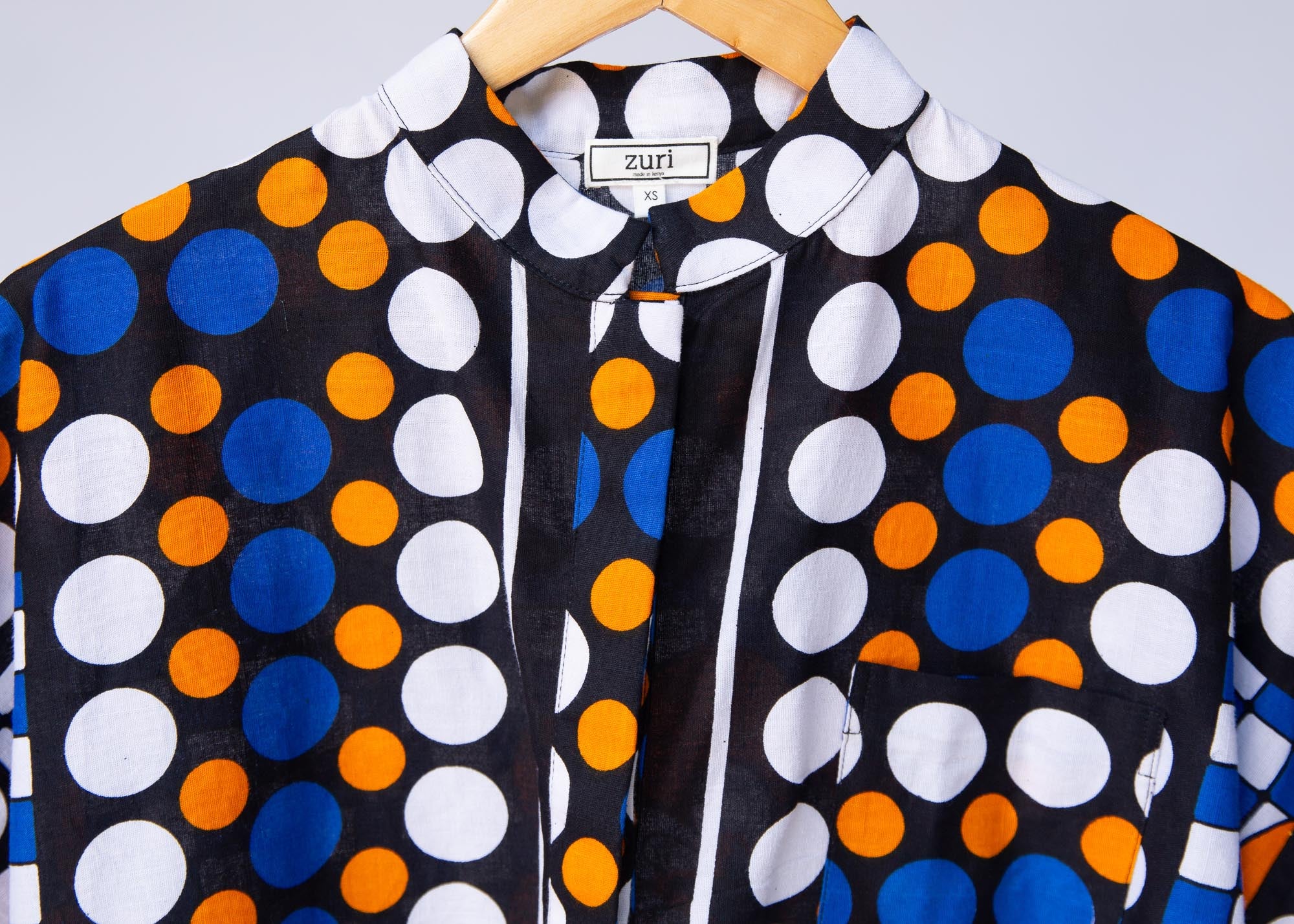 Display of black, white, orange and blue mixed pattern kanga shirt