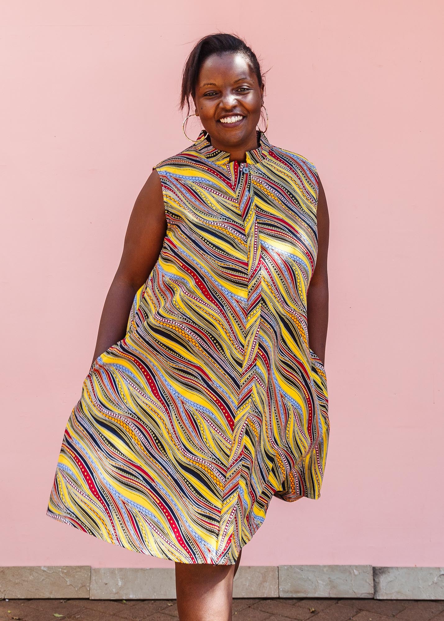 The model is wearing multi-colored abstract print dress