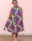 The model is wearing yellow-green dress with purple, black, white fish print 