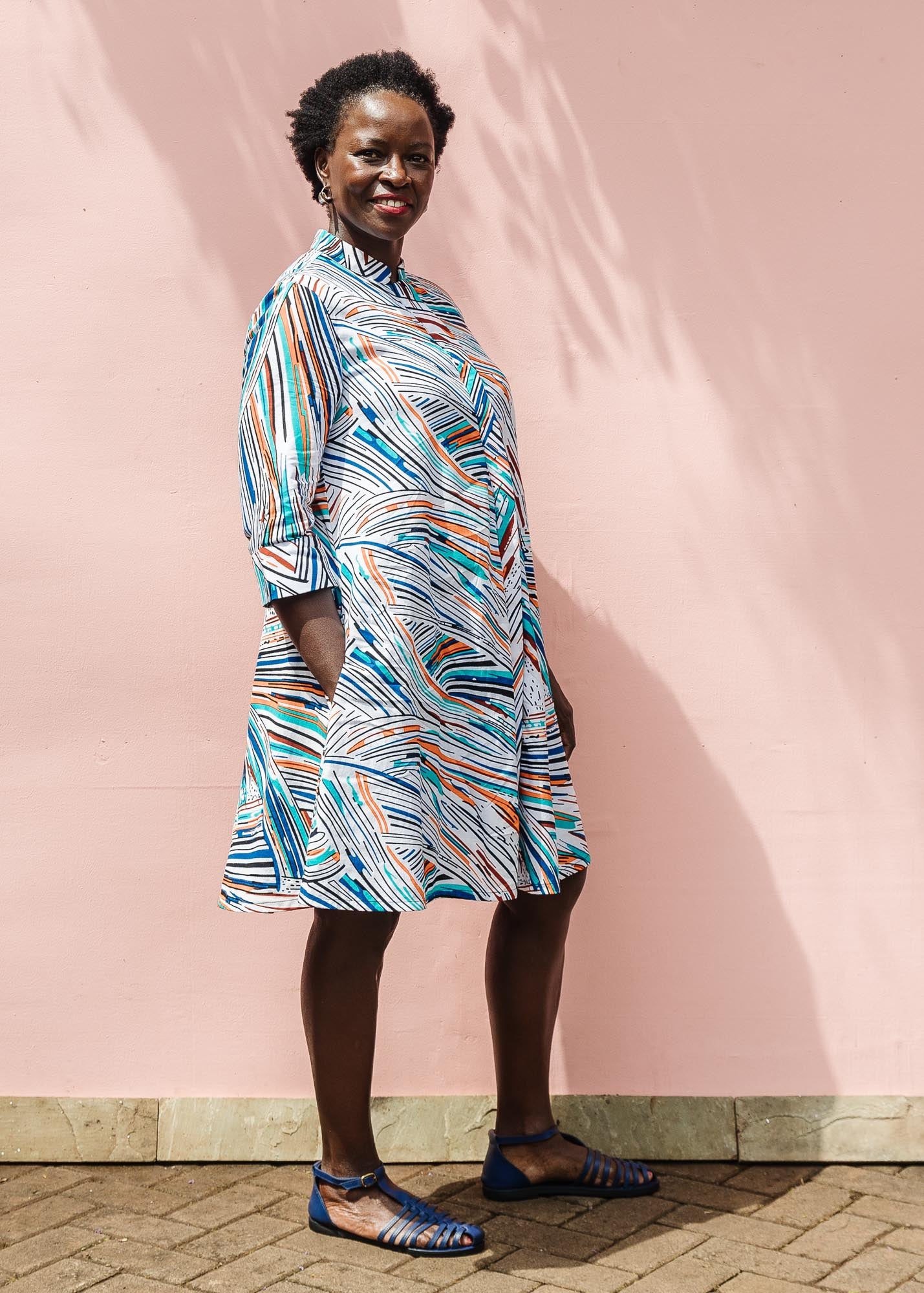 The model is wearing White, black, orange, blue, aqua and brown abstract print dress