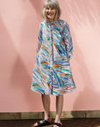 The model is wearing White, black, orange, blue, aqua and brown abstract print dress