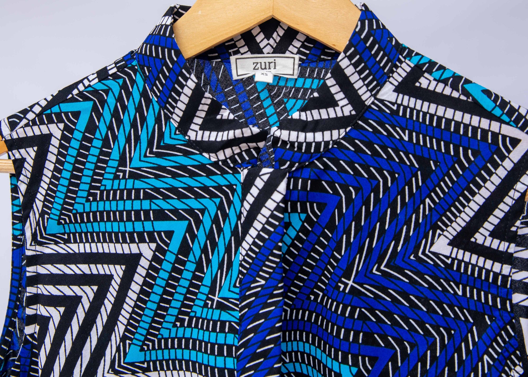 Close up display of blue, aqua and white zig zag print dress.